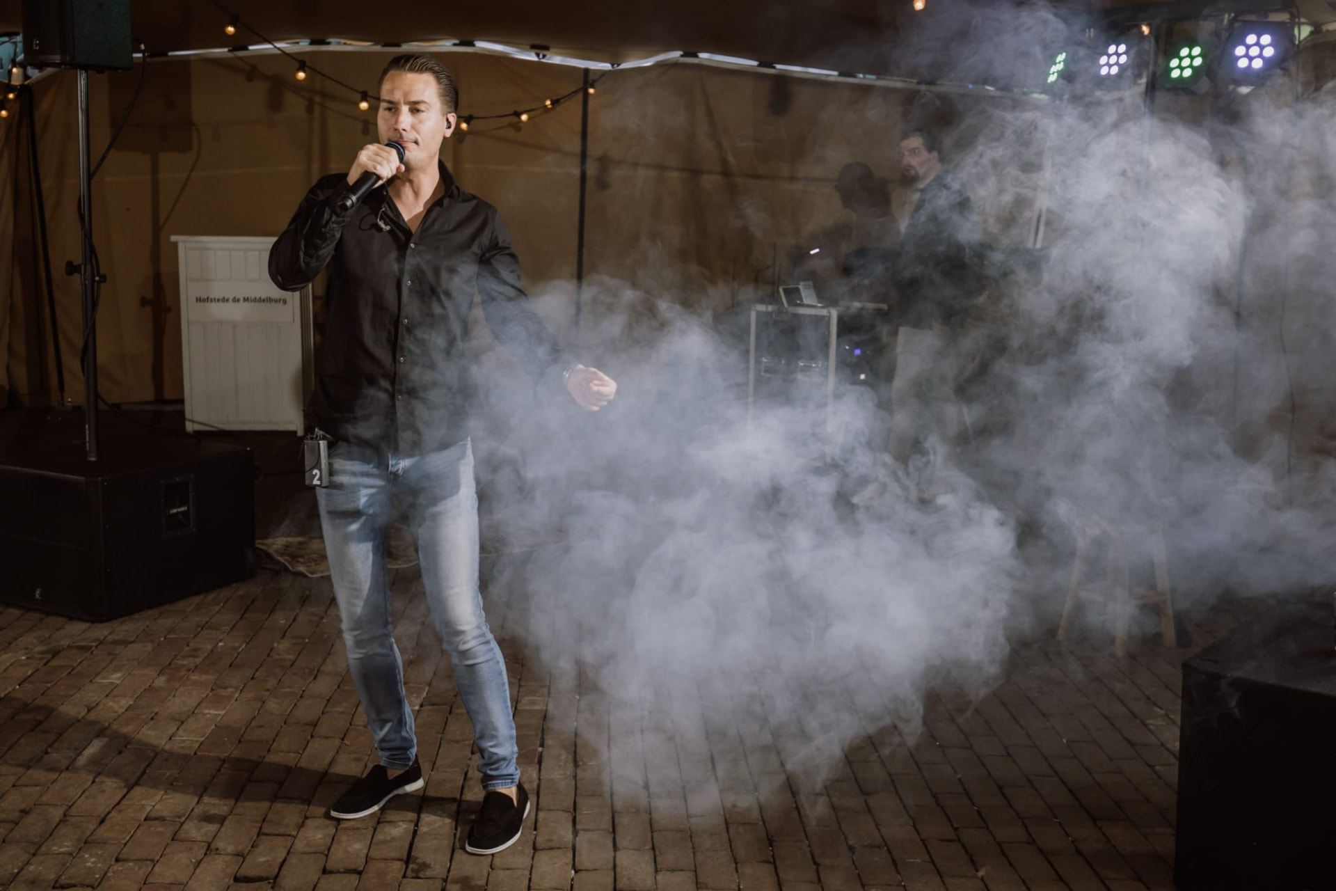 Jermaine Stuiver zingt op een podium omgeven door rook en sfeerverlichting
